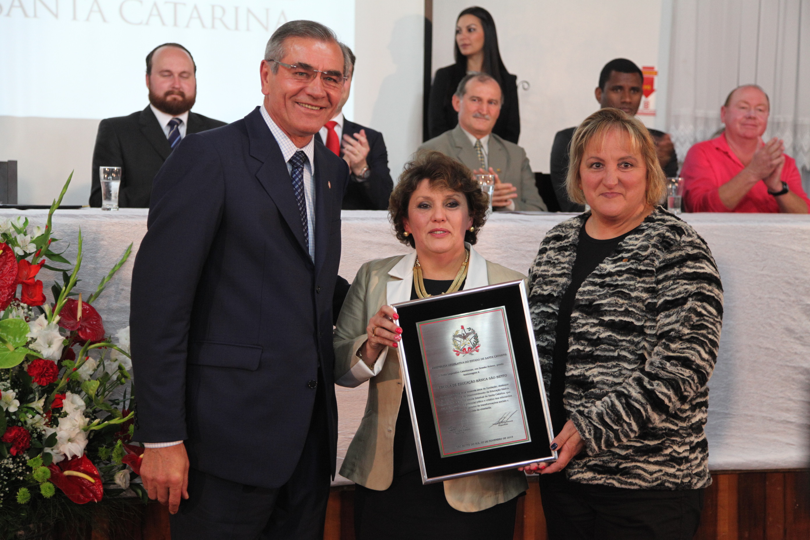 Sessão Solene em Homenagem à Escola de Educação Básica São Bento - Deputado Silvio Dreveck (E), Zuleica Maria Souza (C) e Ariane Lisete Hinke (D), diretoras da Escola de Educação Básica São Bento.