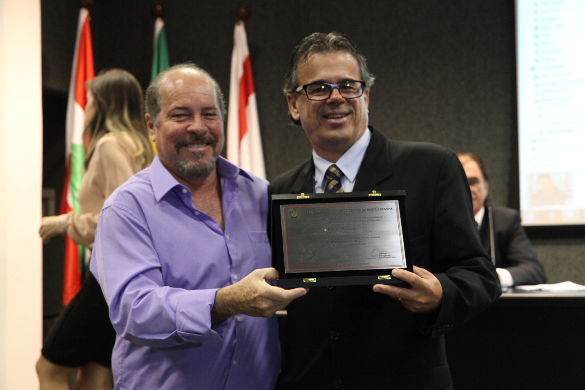 Salles Júnior (E) entrega placa a representante de Sandro Pallaoro