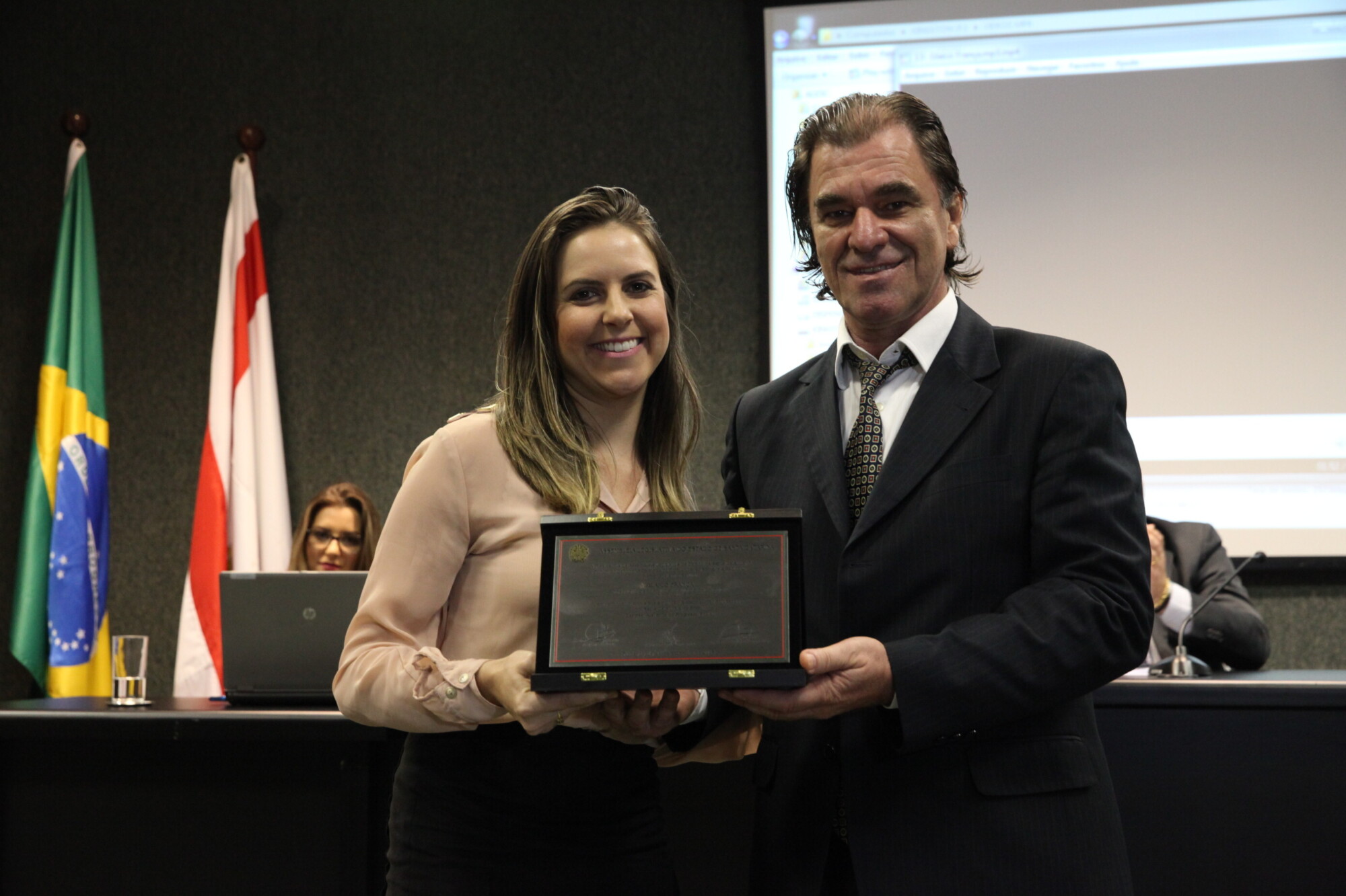 Eduardo Rocha entrega placa a Gicieli Dalpiaz, representante de Glaico França