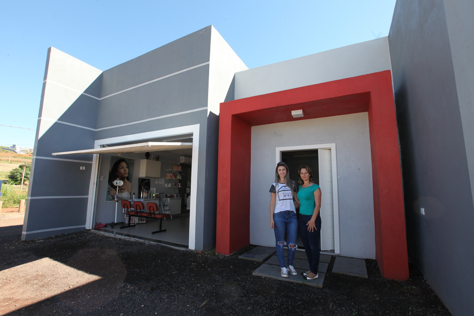 Filha e mãe em frente à residência reconstruída