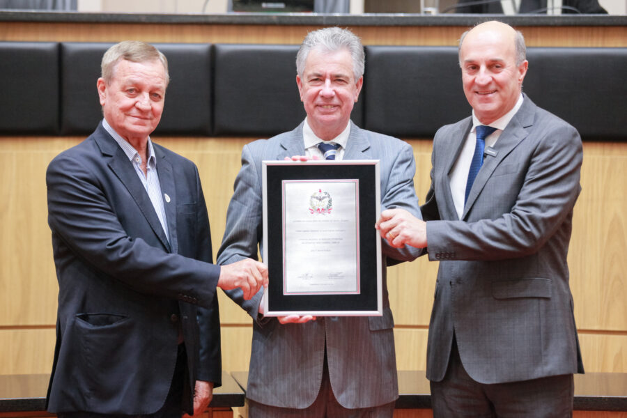 Moacir Tonet recebendo placa celebrativa das mãos do Secretário da Agricultura, Valdir Collato, e do deputado José Milton Scheffer
