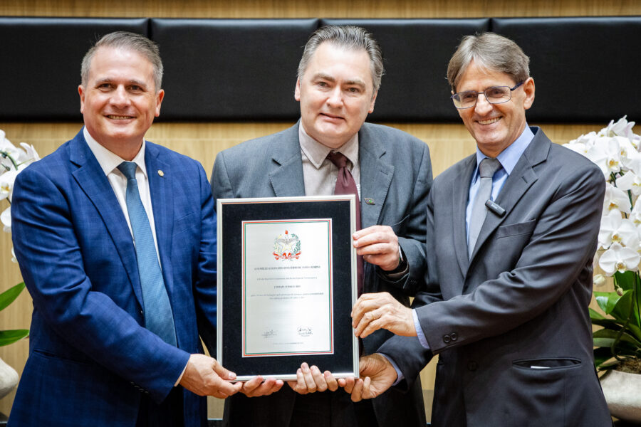 Os deputados Altair Silva (esquerda) e Neodi Saretta (direita), entregaram uma placa comemorativa a Everton Luis Krabbe, da Embrapa Suínos e Aves.